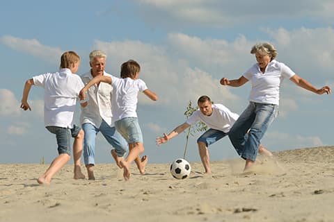 Family playing soccer on beach
